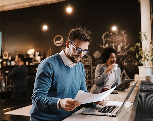 homme souriant ordinateur lisant feuille