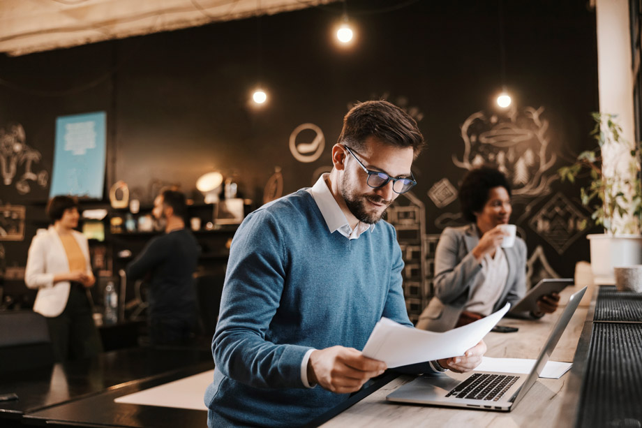 homme souriant ordinateur lisant feuille